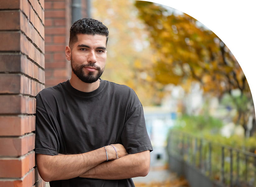 Portrait de Jérémy Grondin accolé à un bâtiment en briques