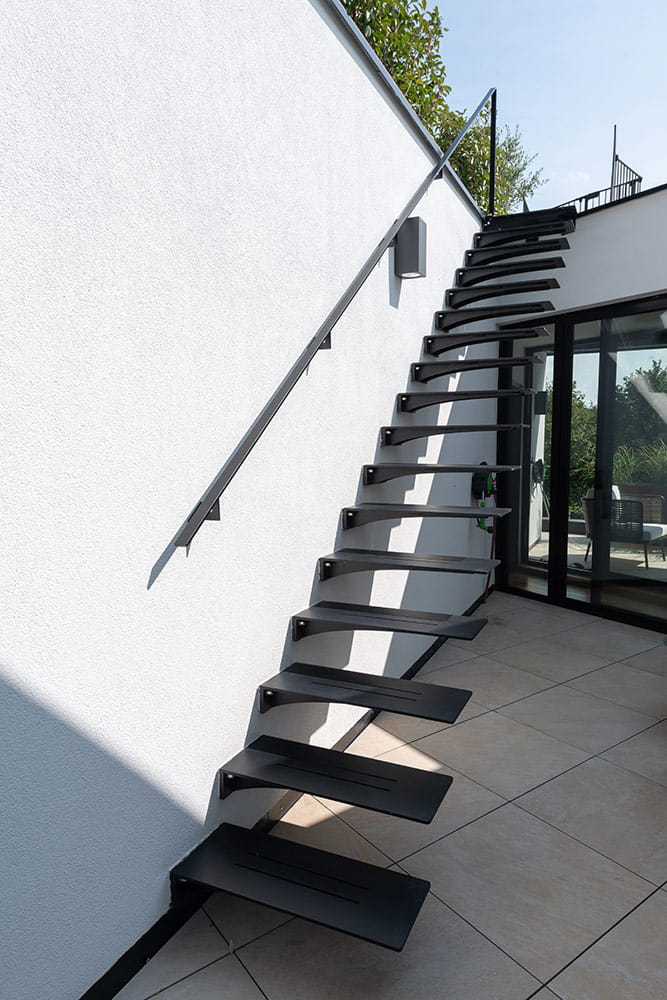 Escalier extérieur métallique, fixé à un mur blanc