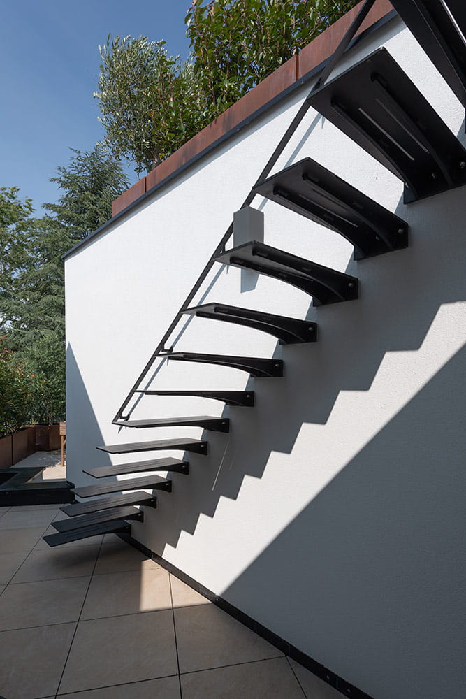 Escalier extérieur métallique, fixé à un mur blanc